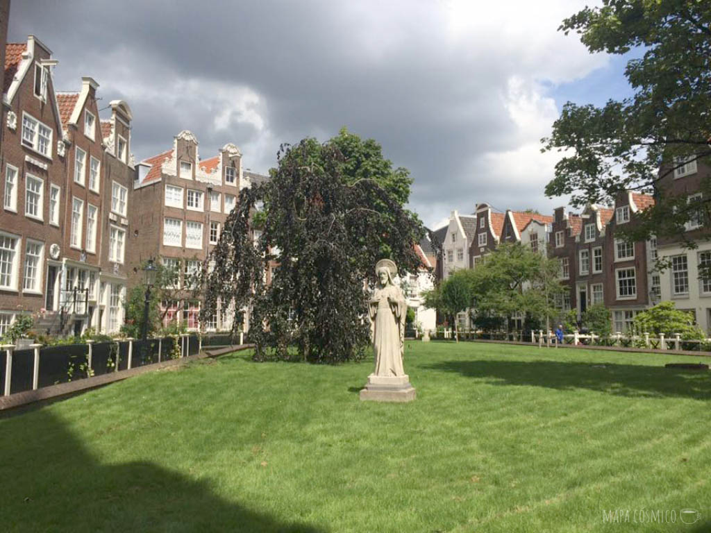 Begijnhof de Amsterdam, plaza medieval con césped, estatua y edificios de viviendas de mujeres