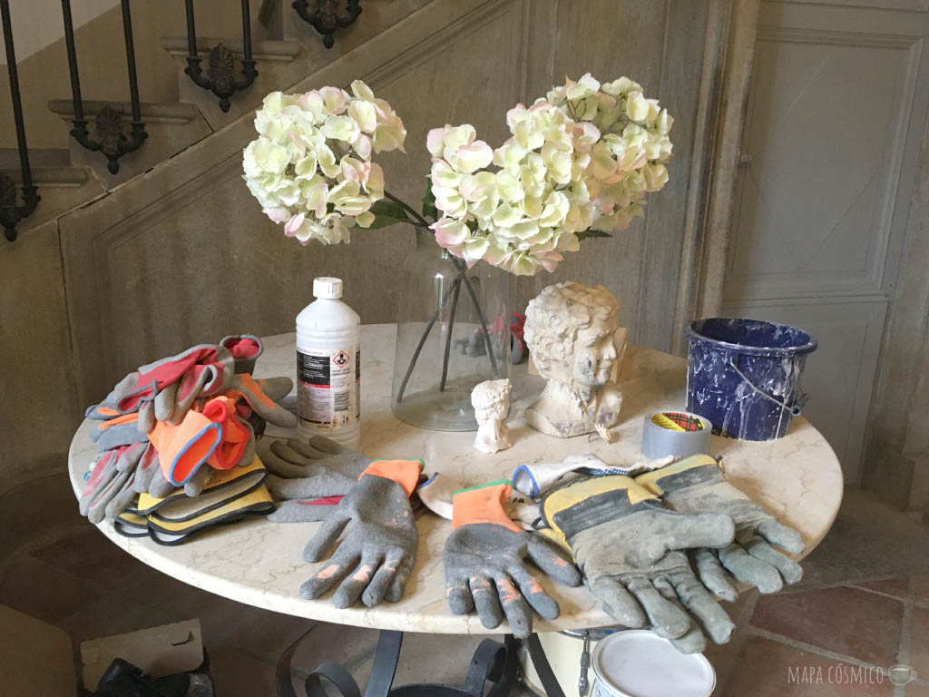 Equipo de trabajo en el voluntariado: guantes y balde en una mesa con flores, restauración de una casona del 1800